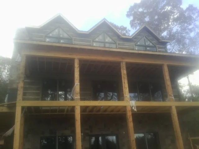 Dormers and porch framing on a large log home under construction — Roof Coating work by our crew in Wheatcroft