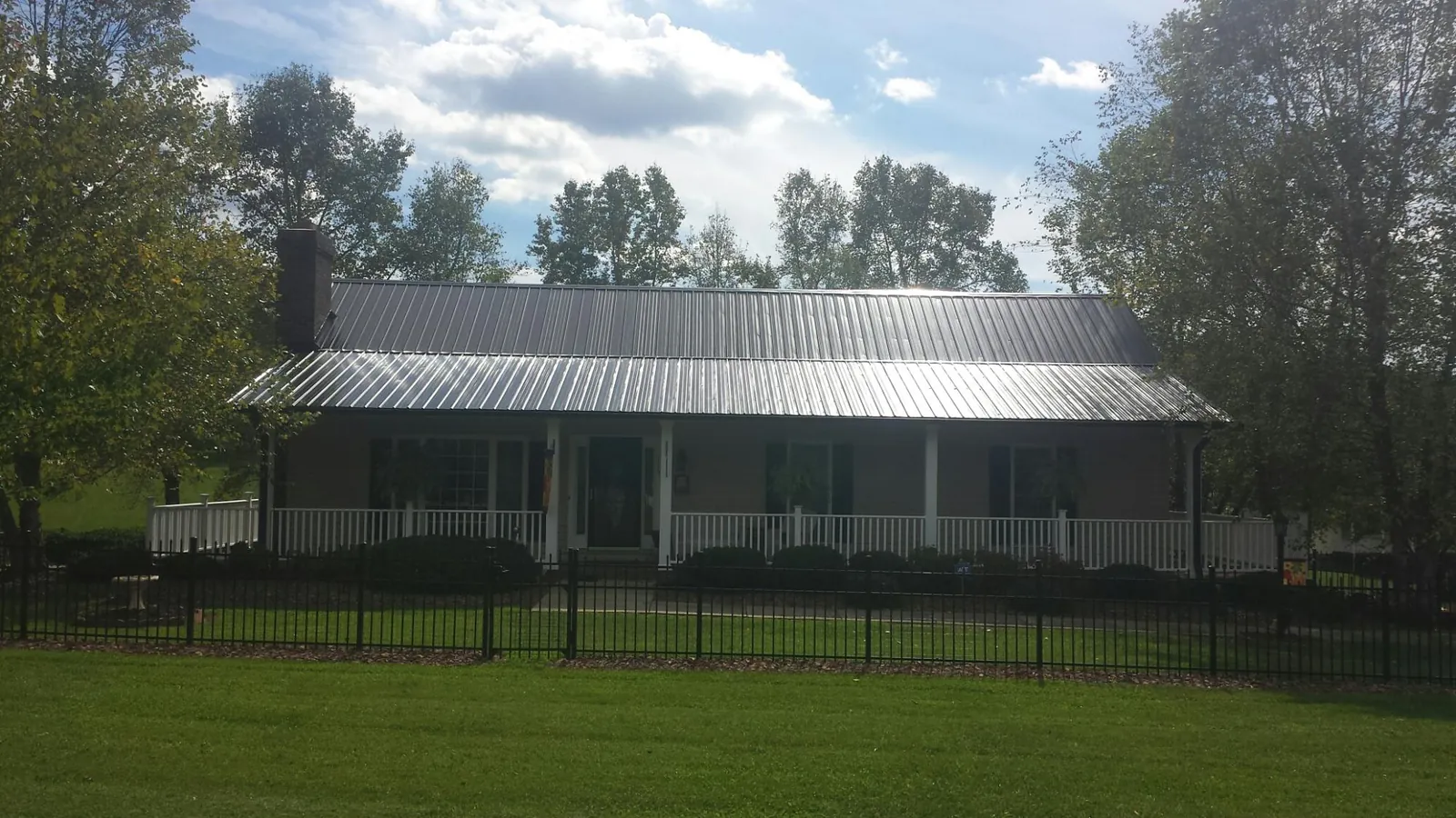 Gray metal roof on a brick ranch with a full width front porch — Gutter Guard Installation work by our crew in Wheatcroft