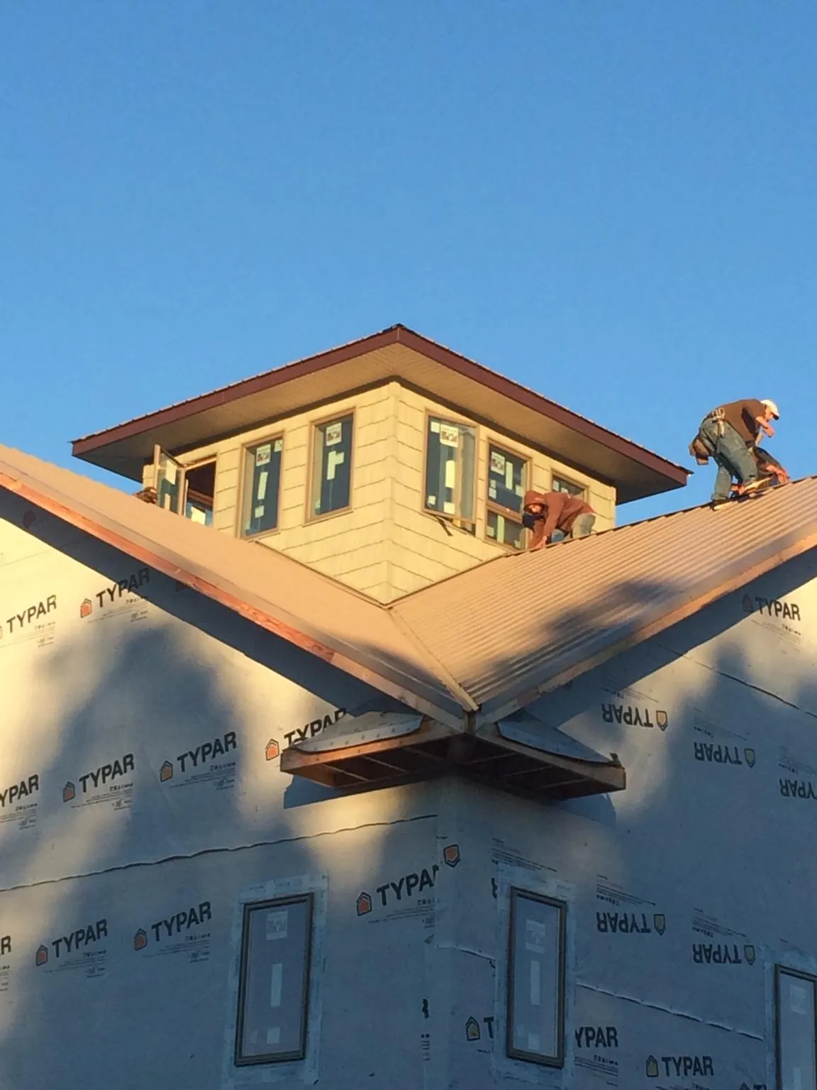 Roofers working around a rooftop cupola on a new metal roof at sunset — Roof Waterproofing in Wheatcroft by Roofing Brothers